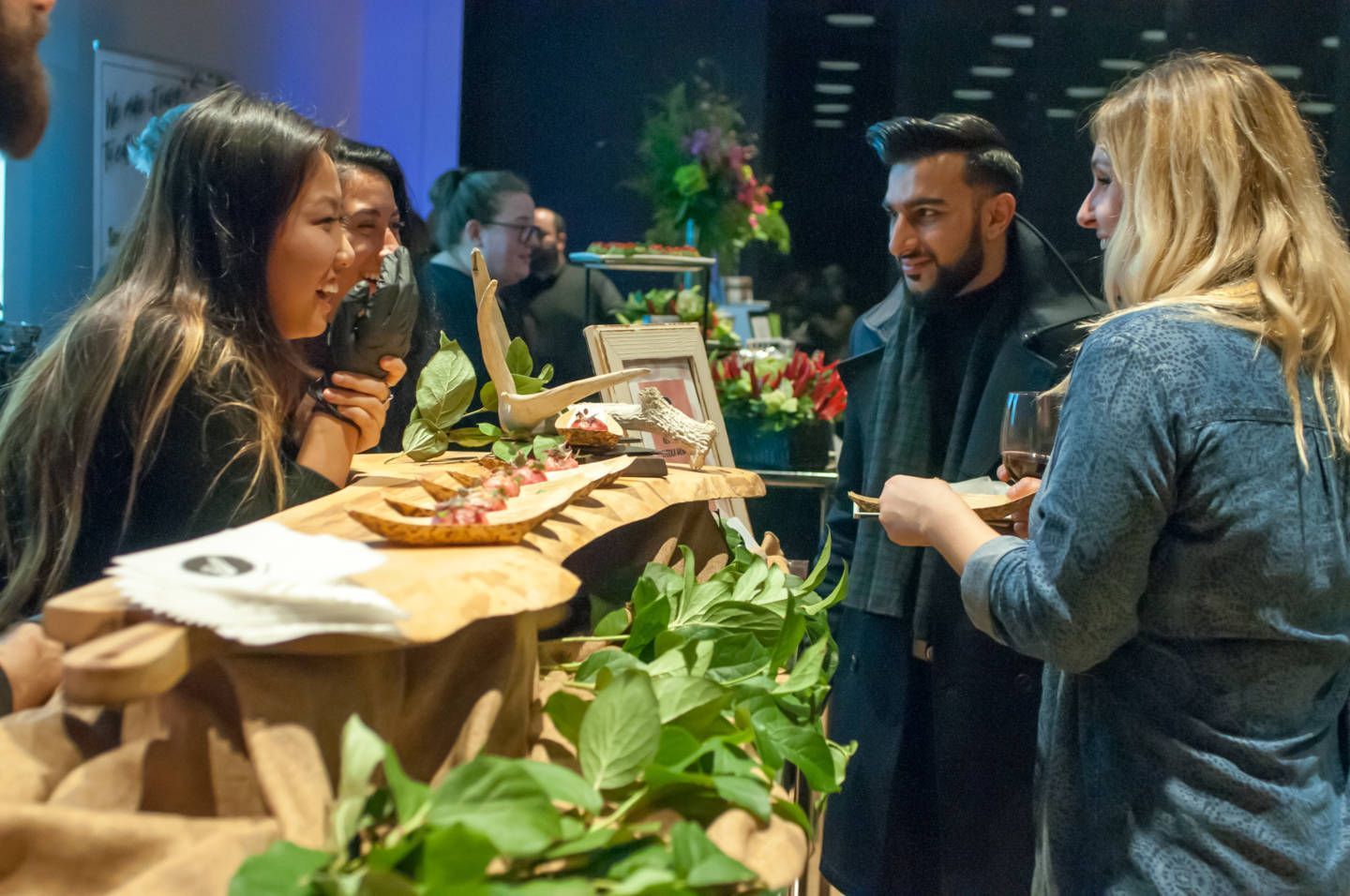 A group of people are standing around a table talking to each other.