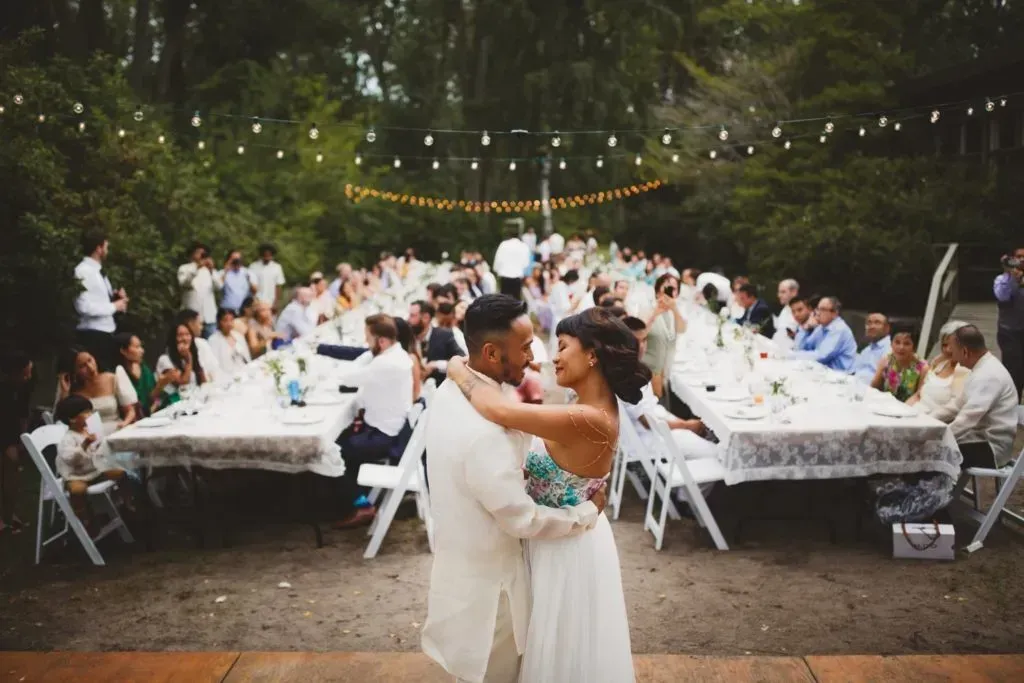 A bride and groom are dancing at their wedding reception in front of a crowd of people.