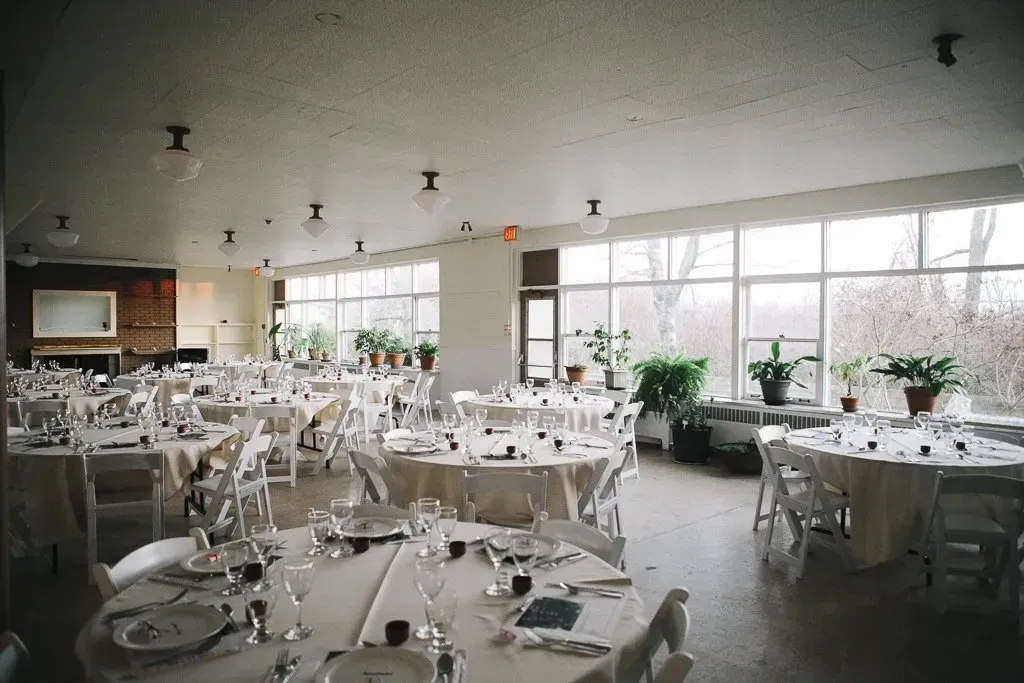 A large room with tables and chairs set up for a wedding reception.