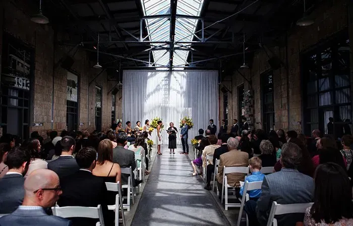 A large group of people are sitting in white chairs at a wedding ceremony.
