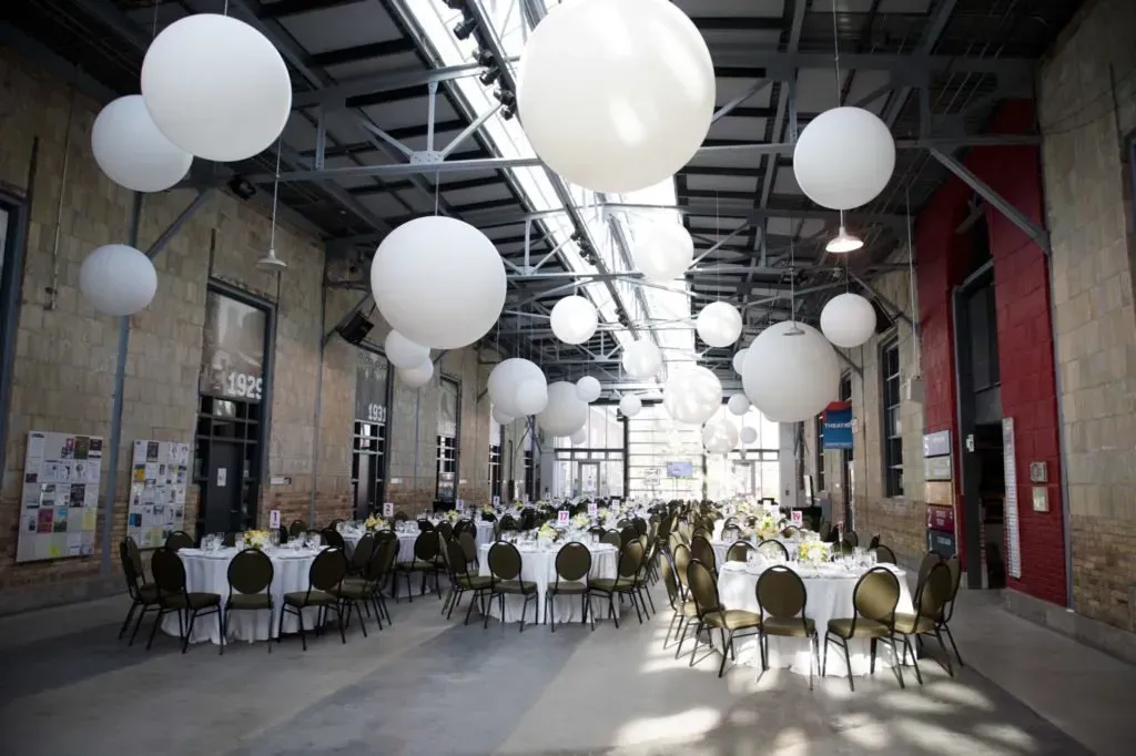 A large room with tables and chairs and balloons hanging from the ceiling