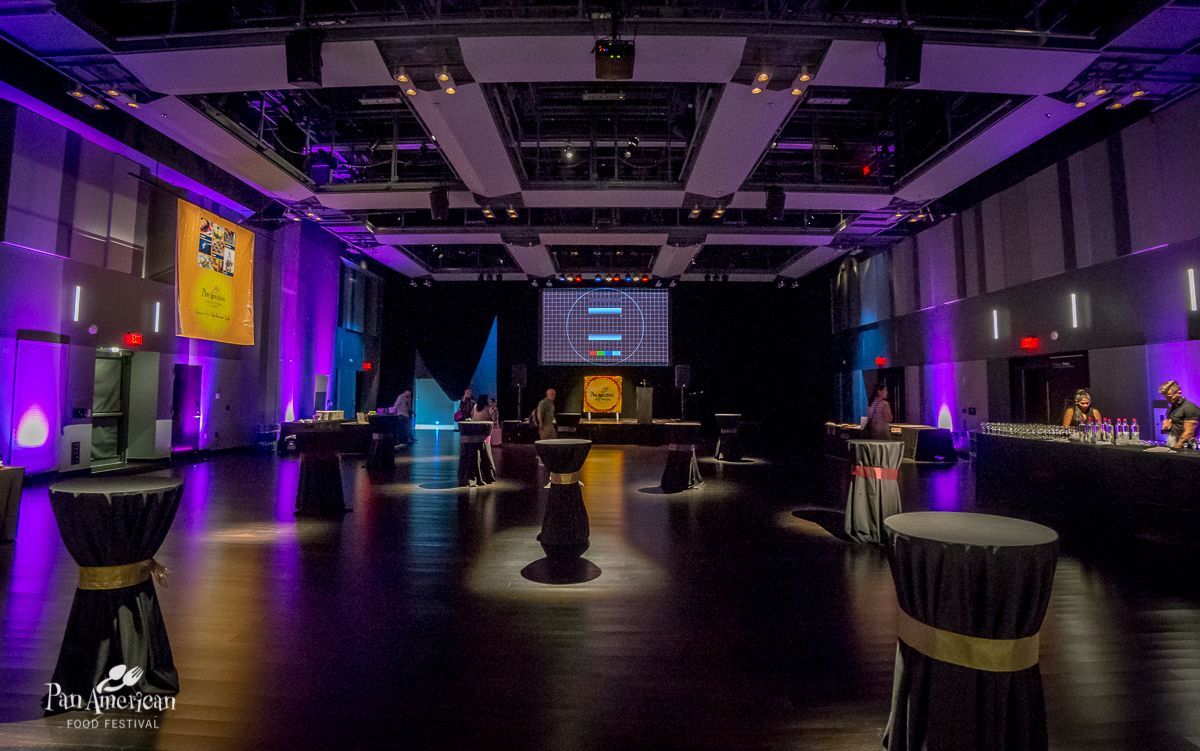 A large room with tables and a large screen on the ceiling.