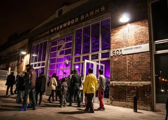 A group of people are standing outside of a building at night.