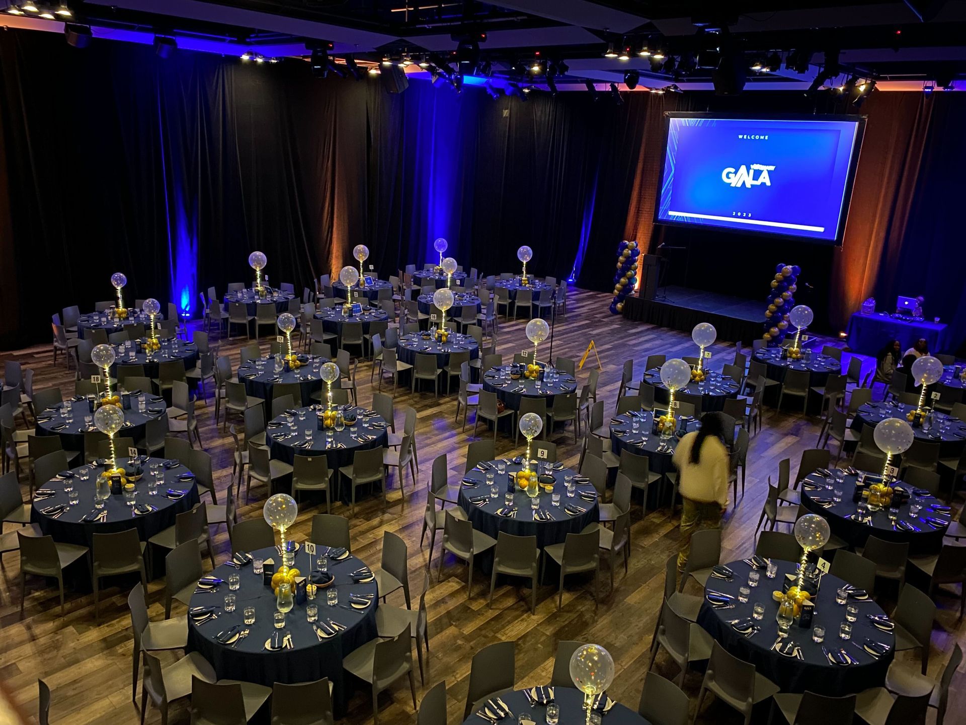 A large room filled with tables and chairs and a large screen.