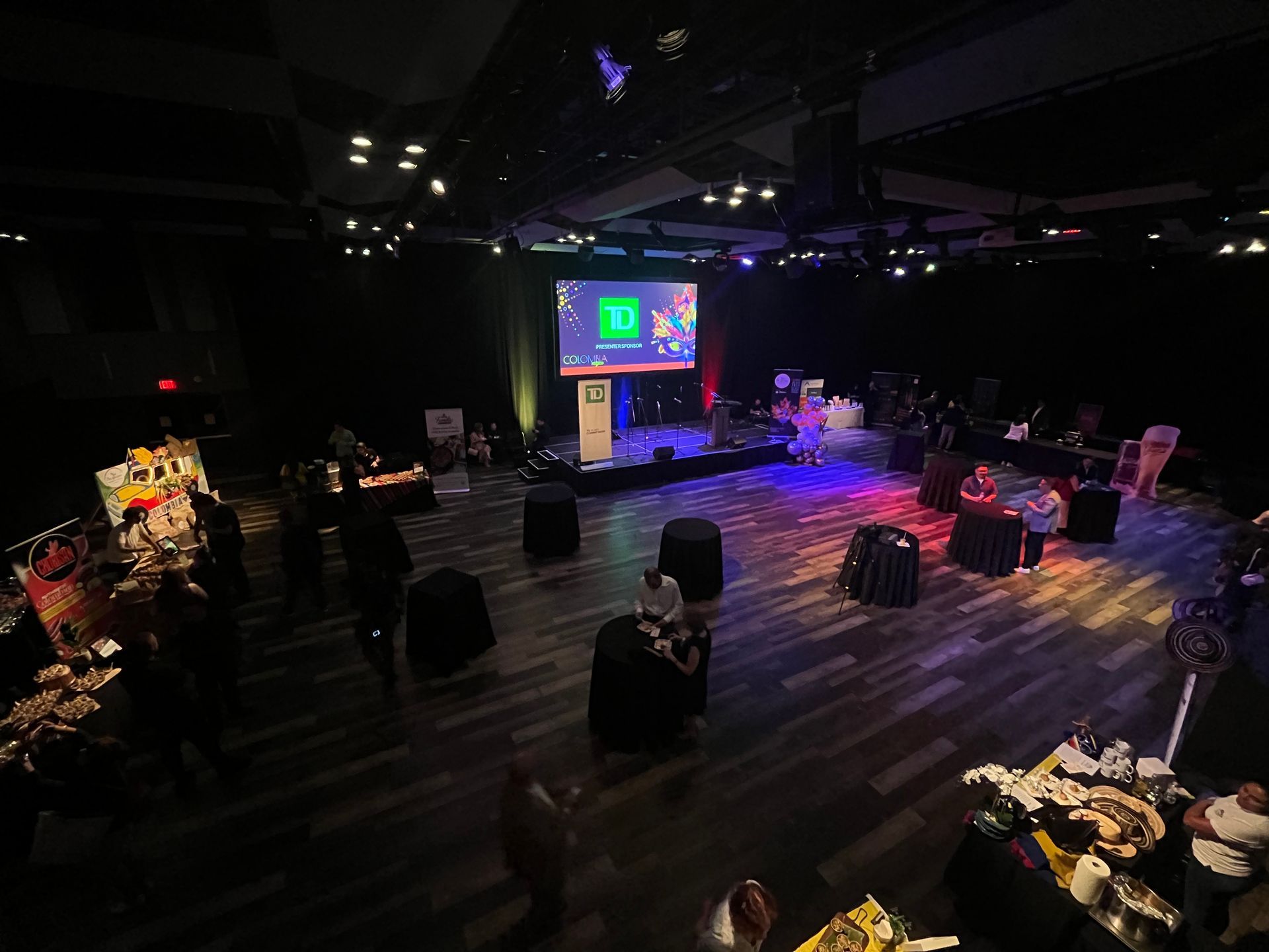 A large room with tables and chairs and a large screen on the wall.