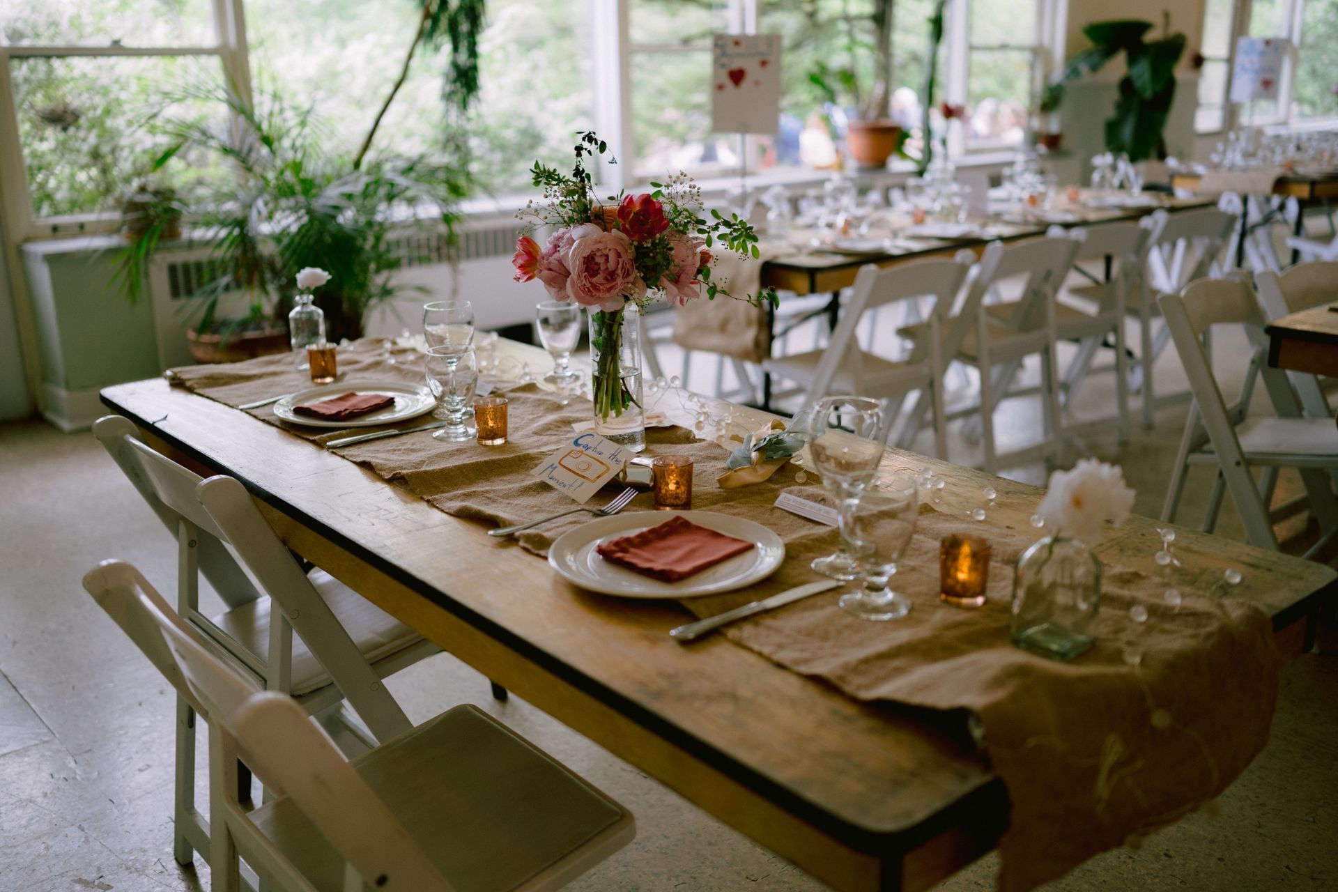 A long wooden table with plates , candles , and flowers on it.