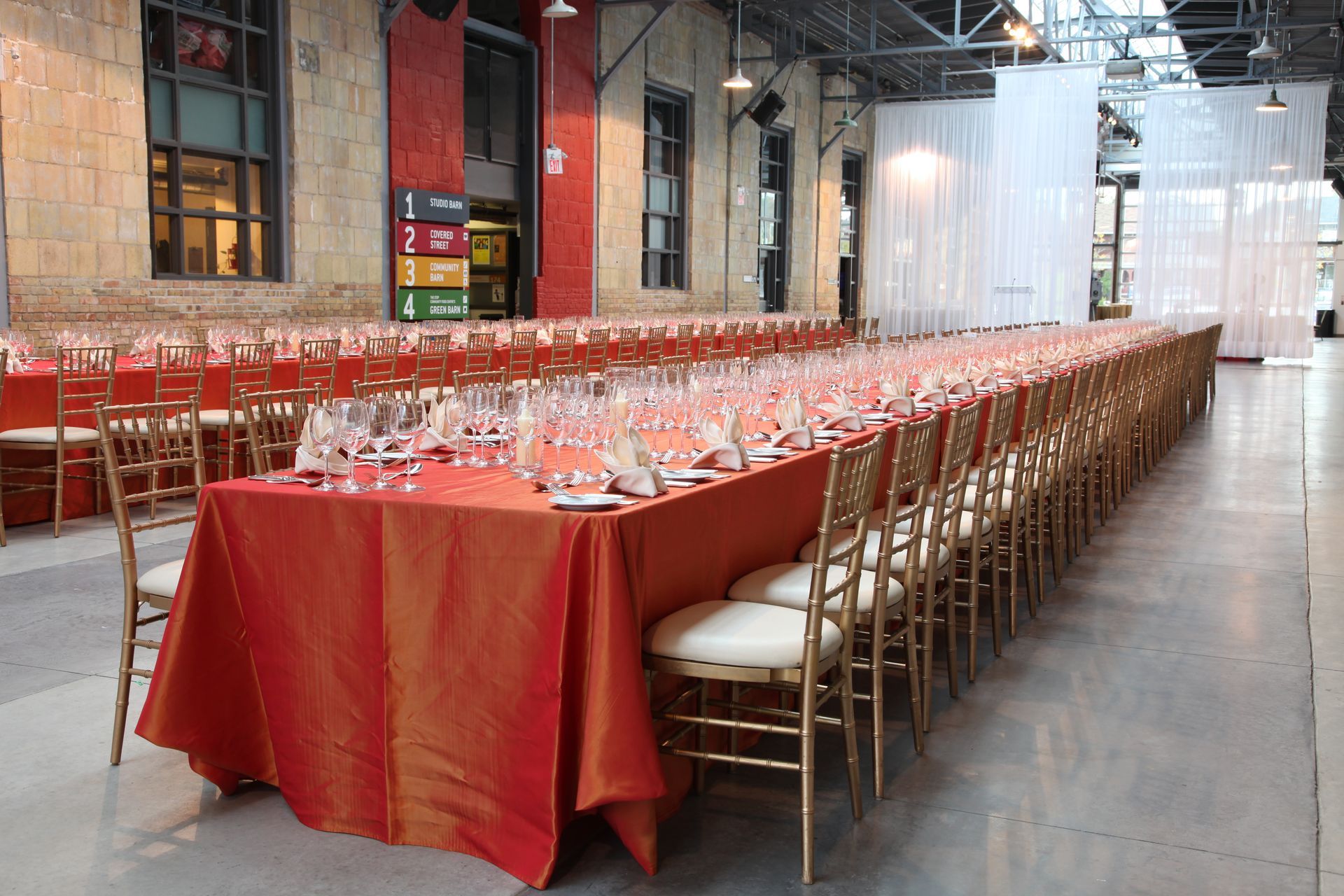 A long table with a red tablecloth and chairs in a large room.