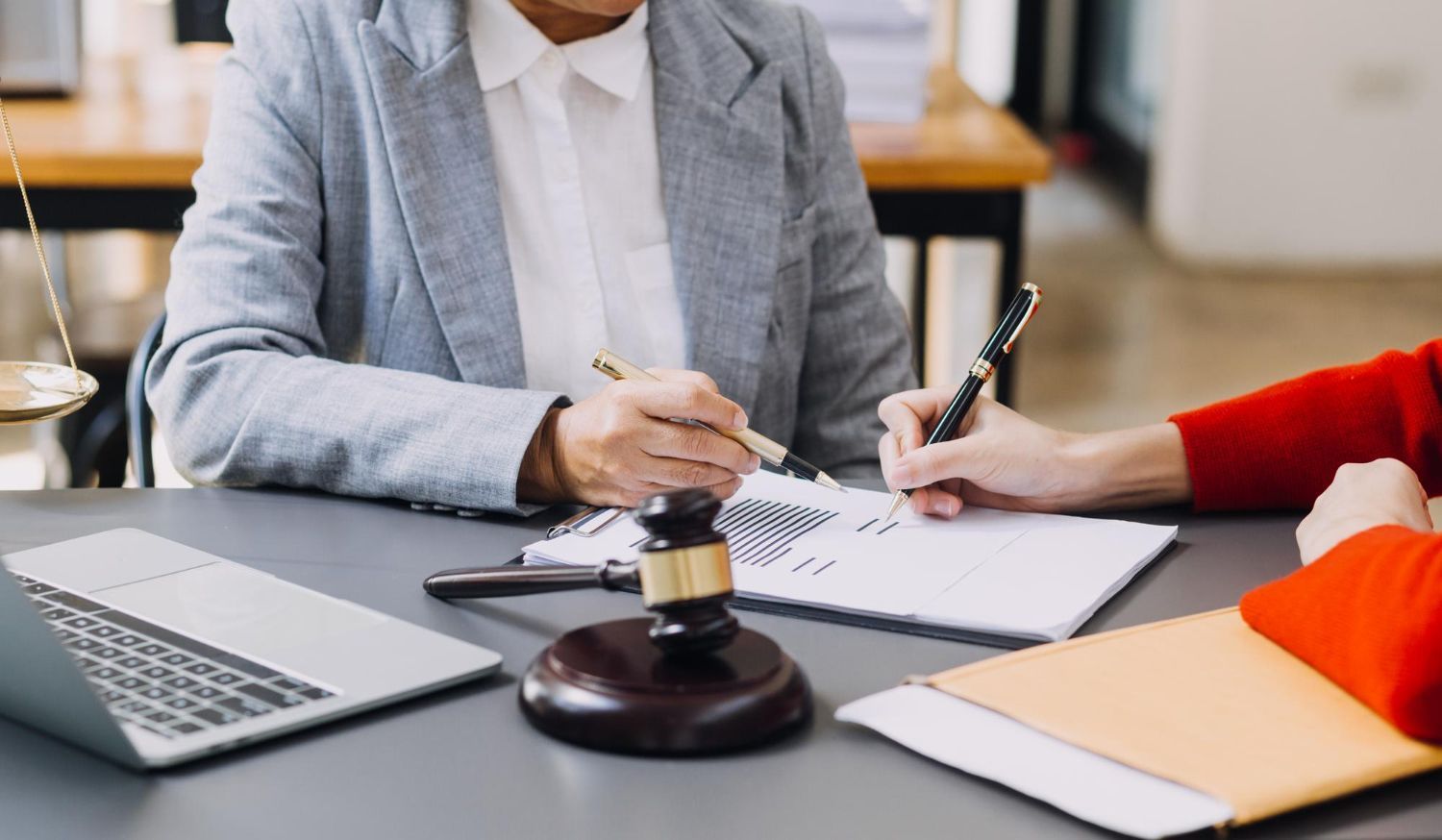 Business meeting with people signing documents beside a judge’s gavel on a table