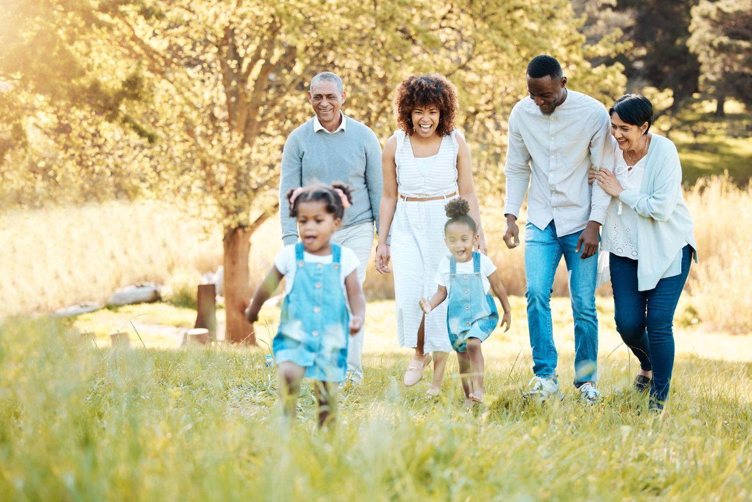 Family walking together through a sunlit grassy field