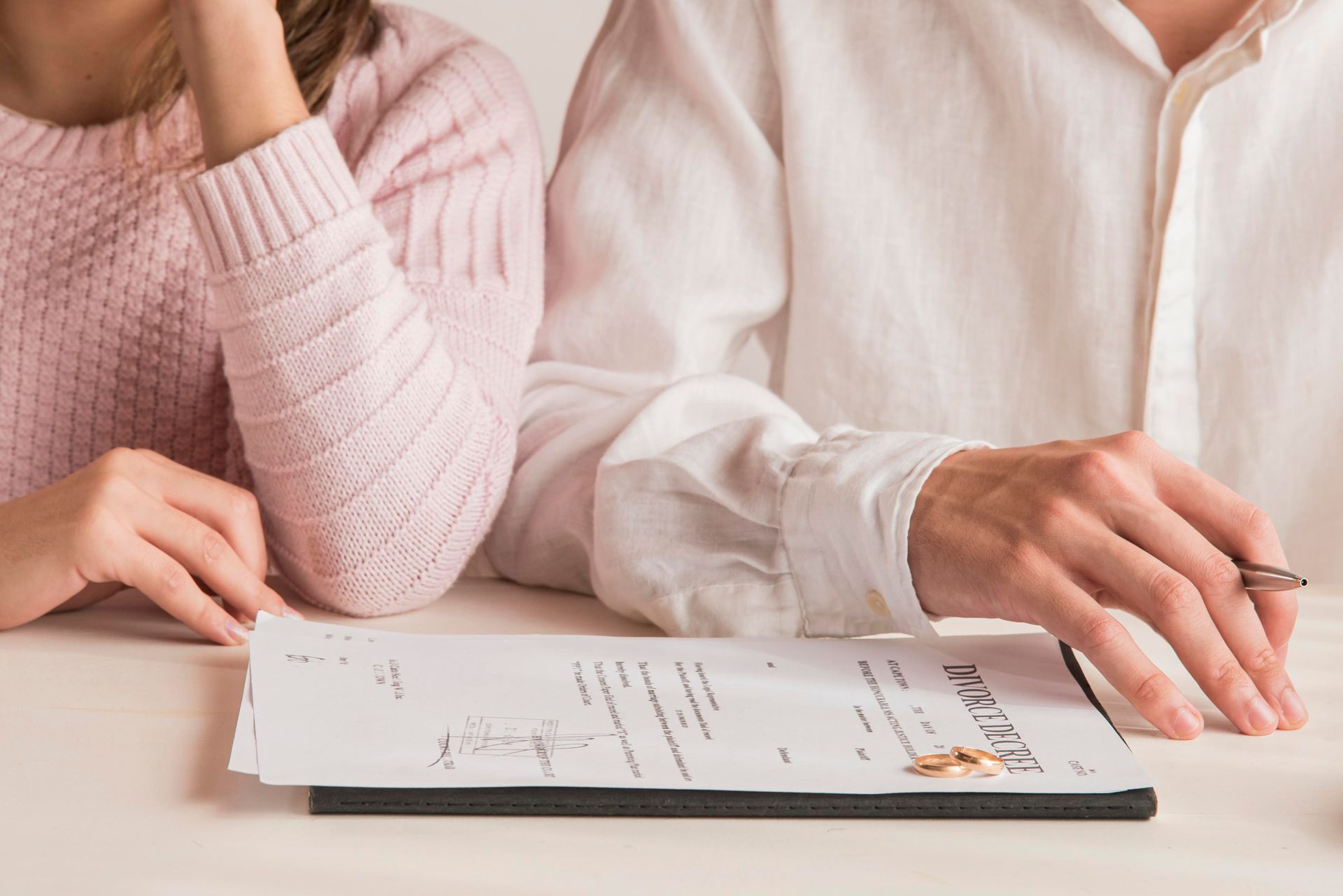 Two people reviewing documents and discussing over a table with a pen and clipboard
