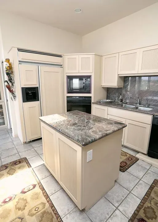 Kitchen with white cabinets, gray countertops, stainless steel appliances, and a central island.
