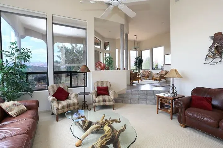 Living room with leather sofas, red chairs, a glass coffee table, and tall windows