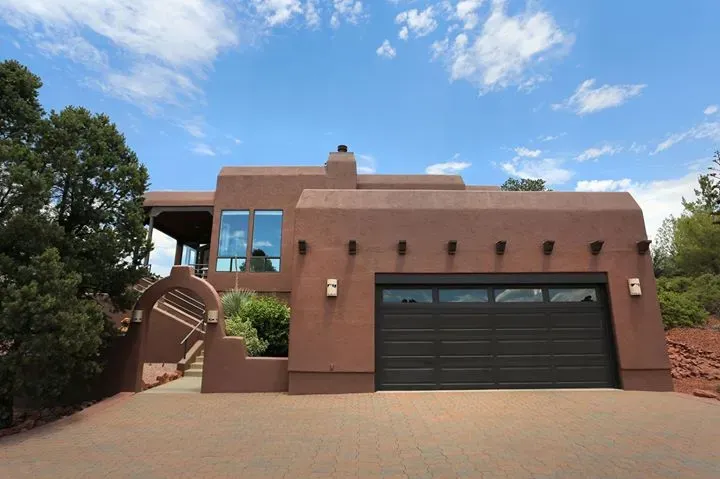 House with stucco facade, black garage door, and desert landscaping