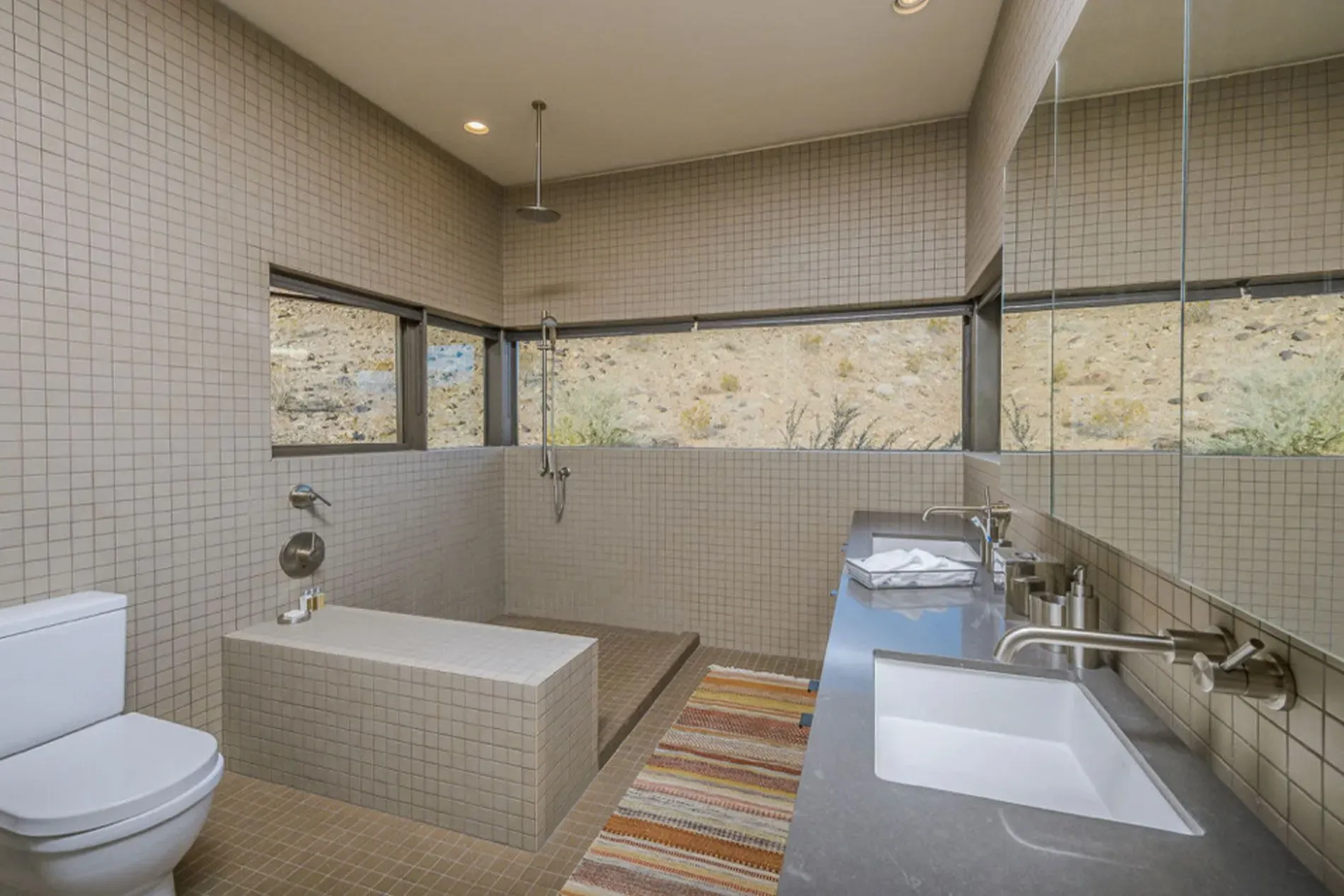 Modern bathroom with a toilet, soaking tub, vanity, and large horizontal windows.
