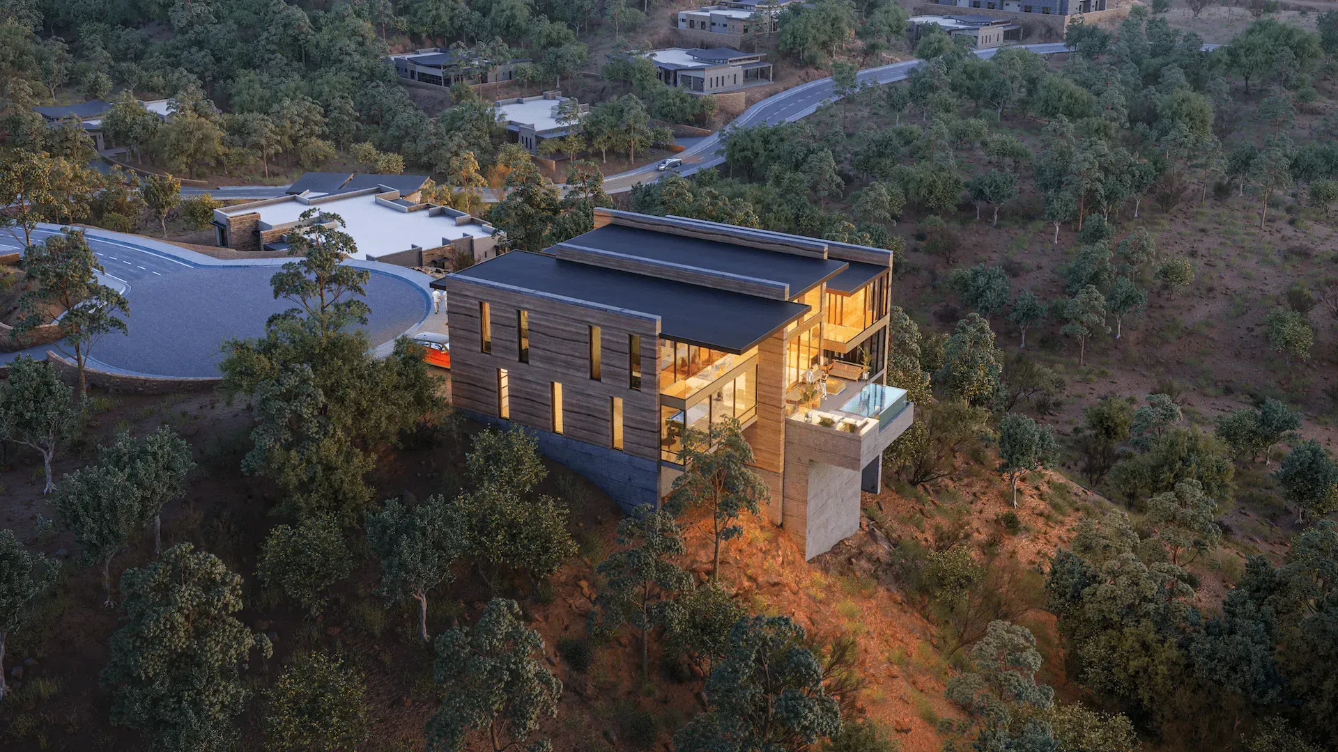 Modern house with warm lights on a wooded hillside at dusk
