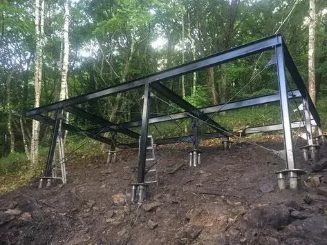 Black metal platform on concrete posts in a forested hillside clearing