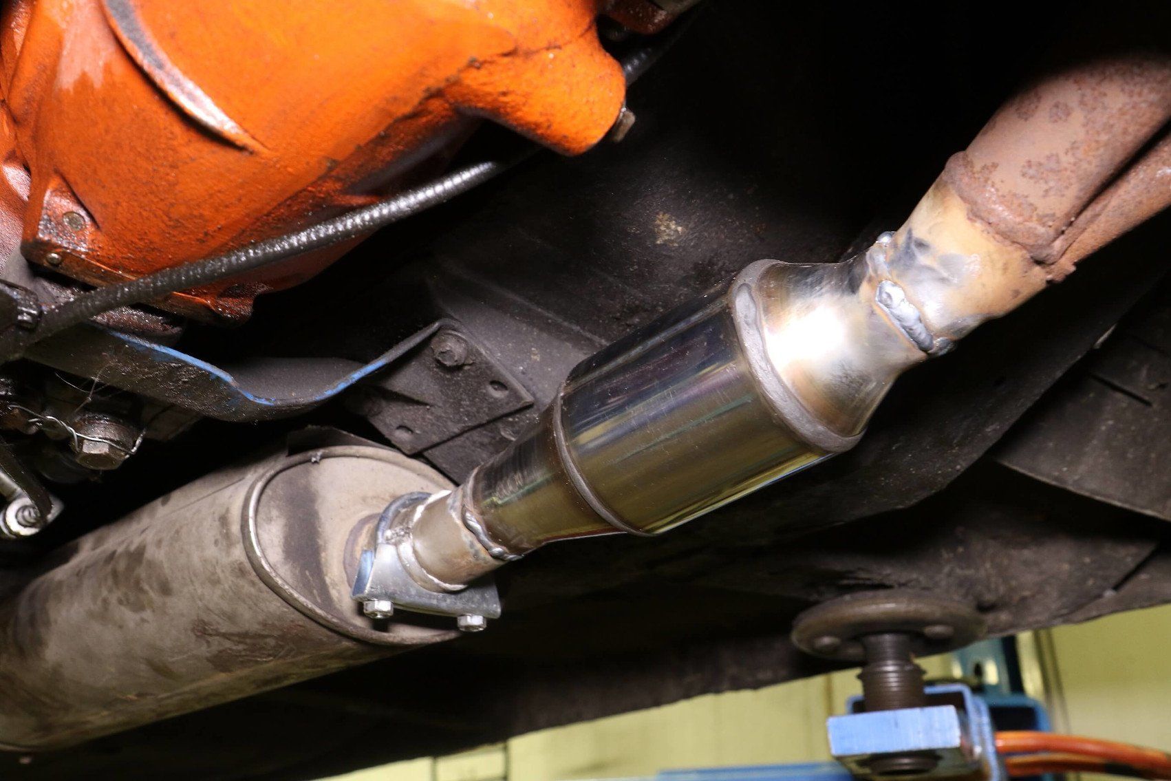 A close up of a car exhaust pipe with a catalytic converter attached to it.