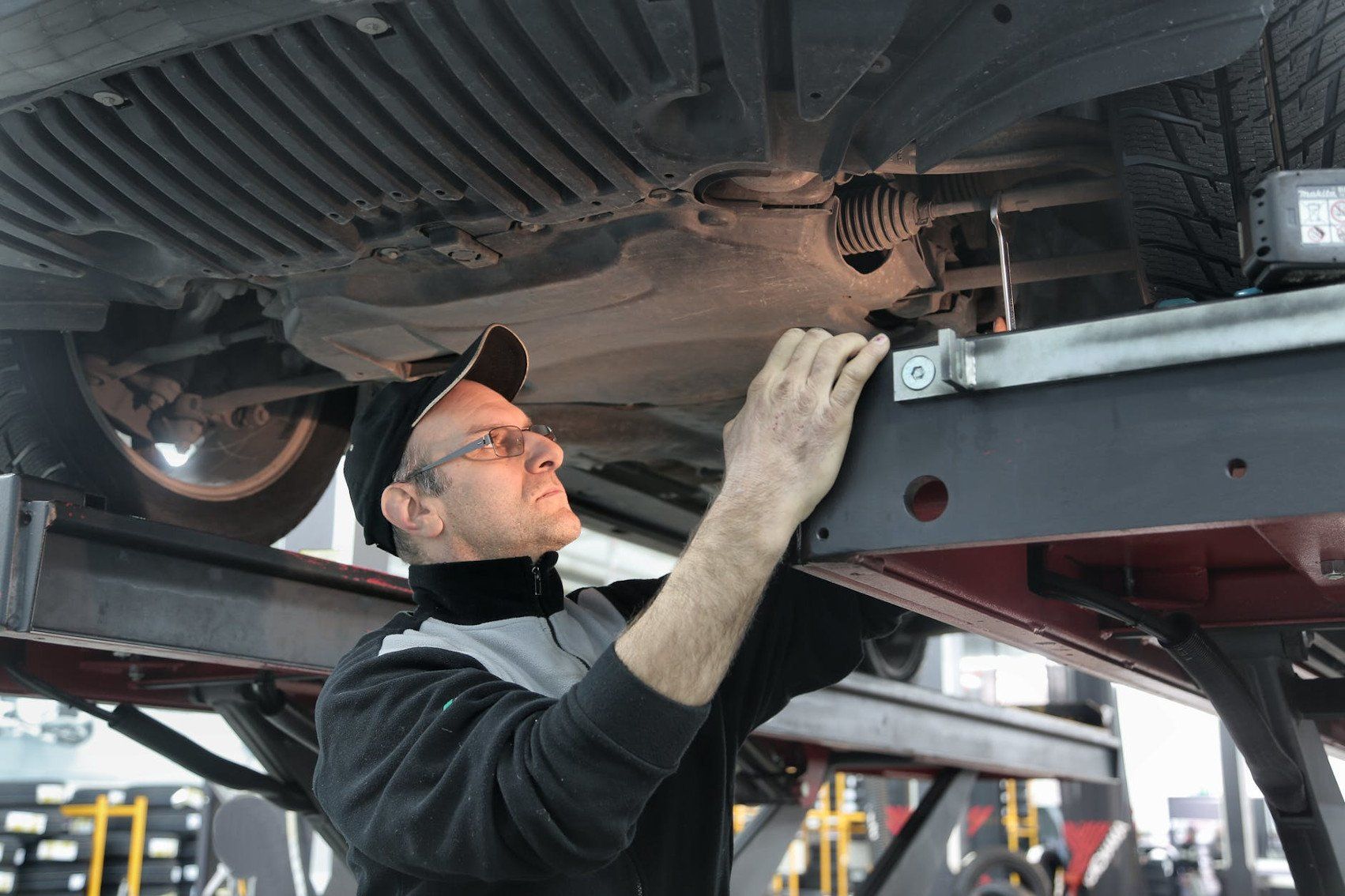 A man is working under a car in a garage.