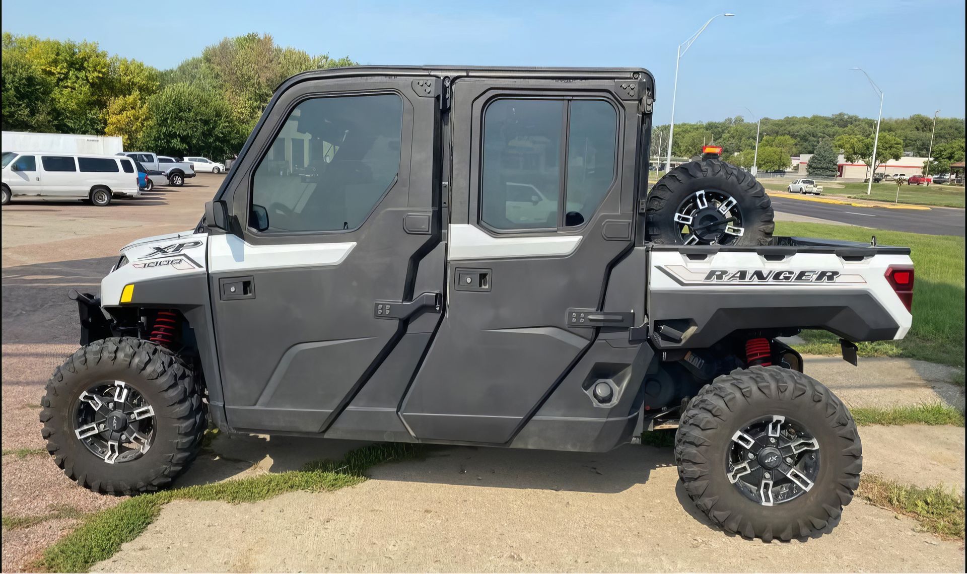 Black-and-white side-by-side off-road utility vehicle parked on a paved lot, side view.