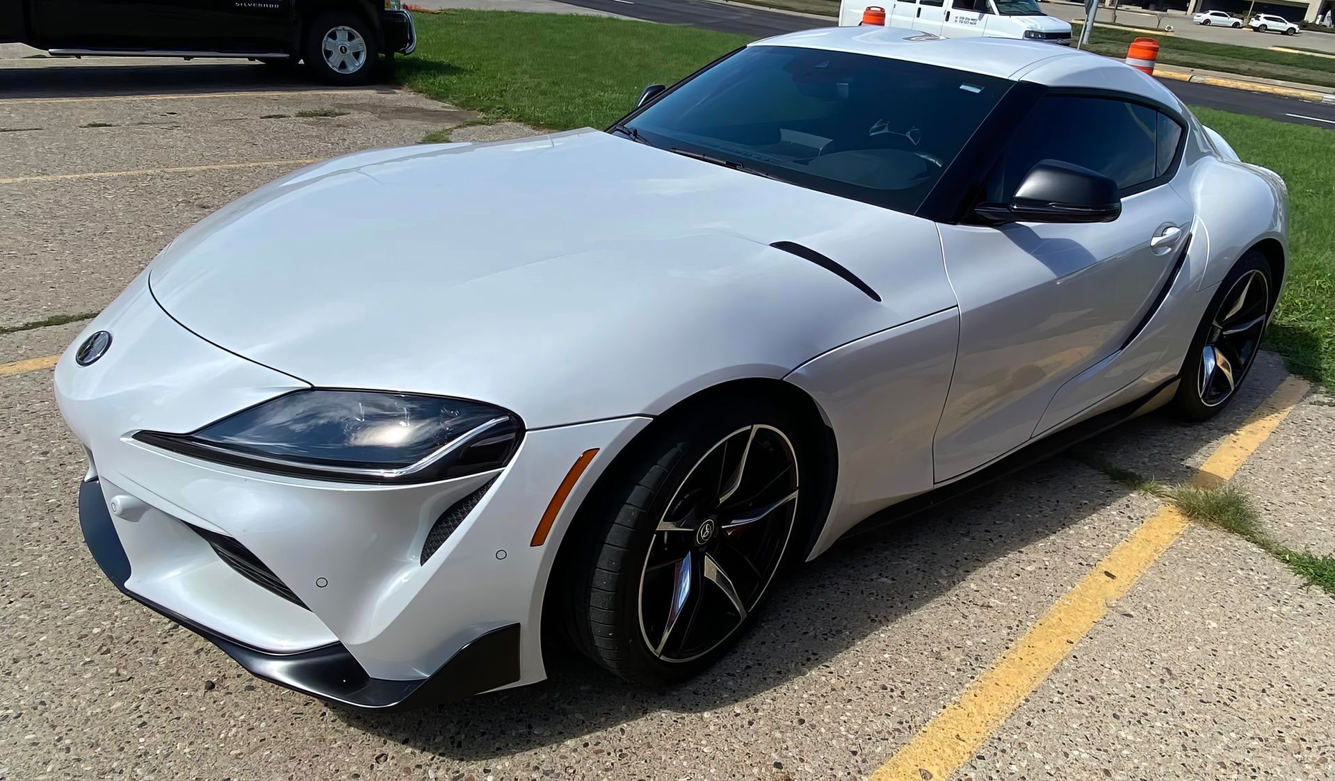 White sports car parked in a lot, viewed from the front-left side.
