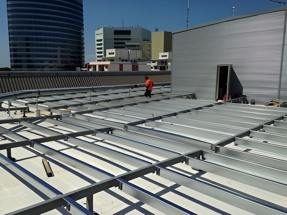 A Man Is Standing On The Roof Of A Building — Jakes Steel & Welding in East Arm, NT