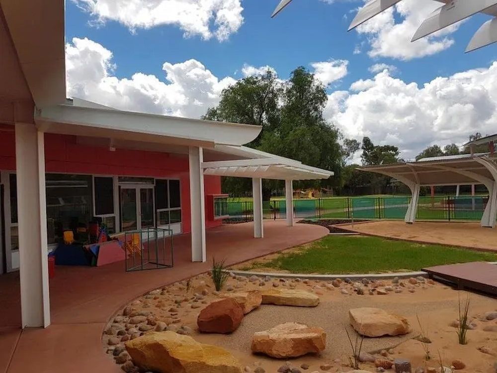 A Pink Building With A White Roof Is Surrounded By Rocks And Grass — Jakes Steel & Welding in East Arm, NT