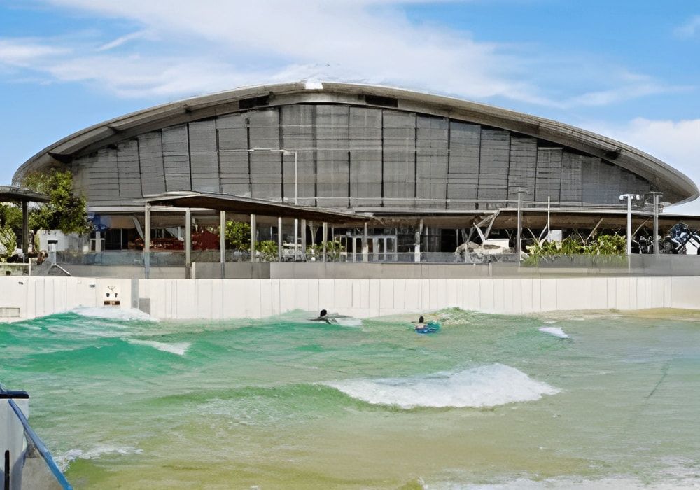 A Group Of People Are Surfing In Front Of A Large Building — Jakes Steel & Welding in East Arm, NT