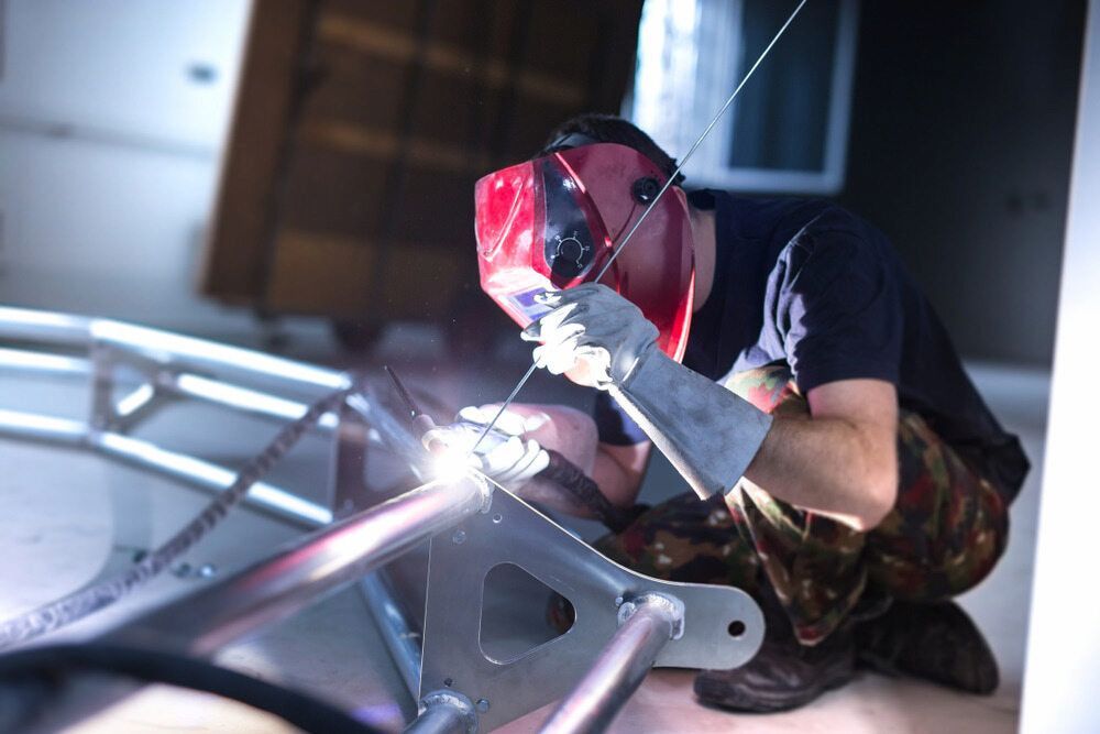 A Man Wearing A Welding Mask Is Welding A Piece Of Metal — Jakes Steel & Welding in East Arm, NT