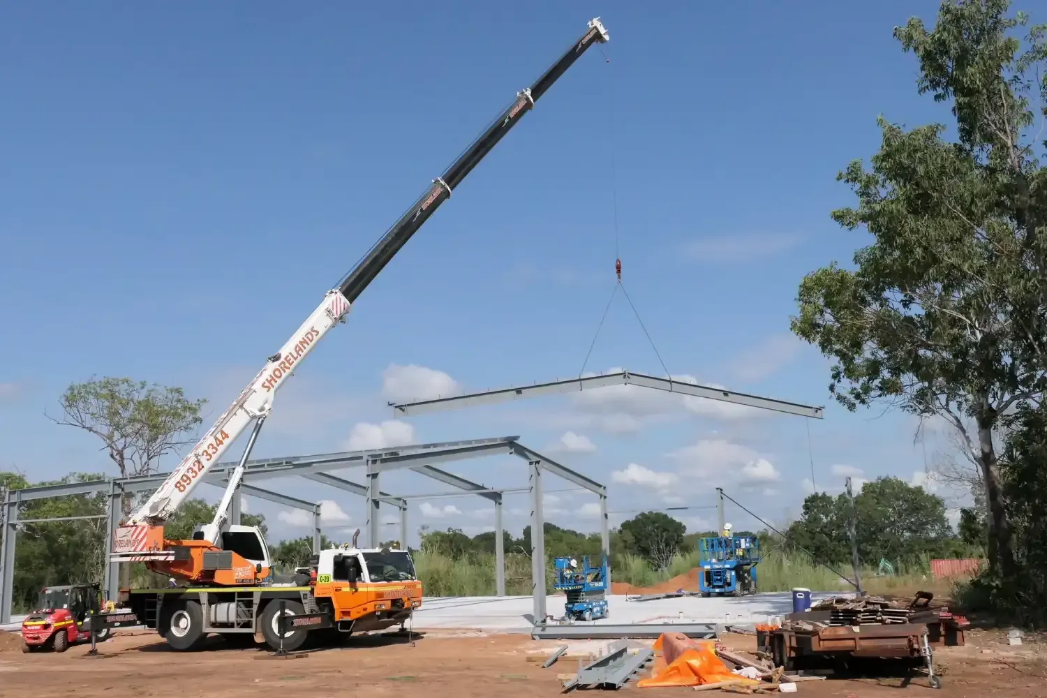 A Large Crane Is Lifting A Metal Structure On A Construction Site — Jakes Steel & Welding in East Arm, NT
