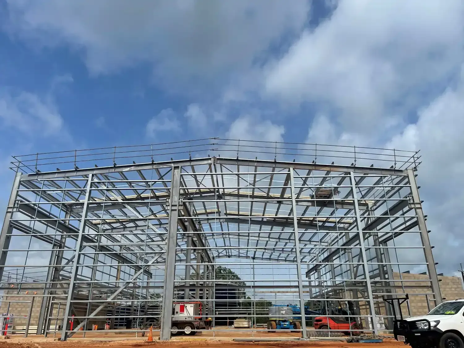 A Large Metal Building Under Construction With A Truck Parked In Front Of It — Jakes Steel & Welding in East Arm, NT