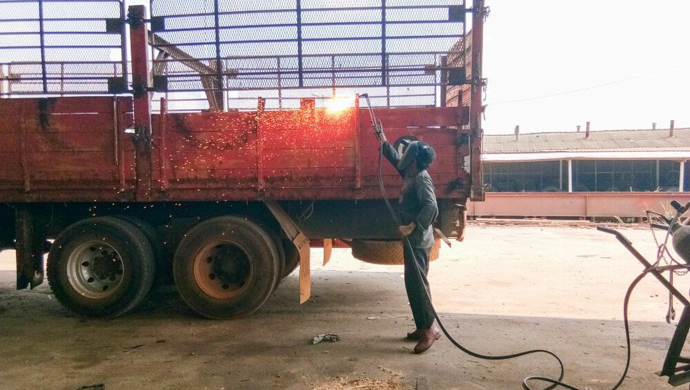 A Man Is Welding A Truck In A Garage — Jakes Steel & Welding in East Arm, NT