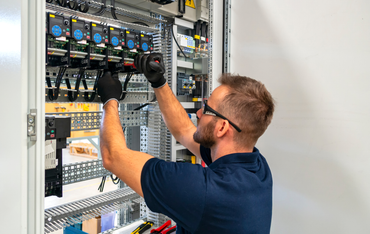 Electrician adjusting wiring inside an open control panel
