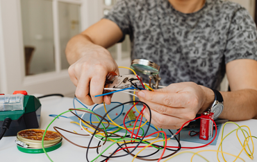 Person soldering wires at a workbench during electrical repair