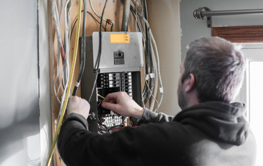 Technician wiring an electrical breaker panel in a utility room