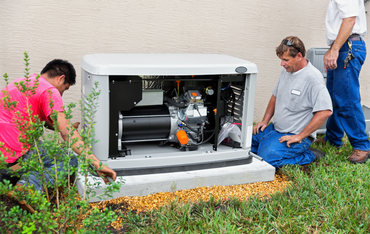 Workers inspecting an outdoor backup generator cabinet