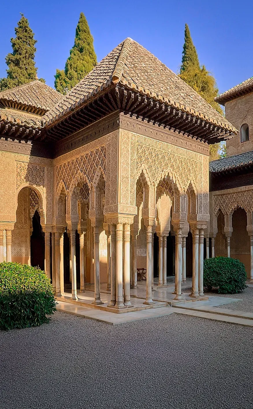 Courtyard view of an ornate, Moorish-style pavilion with detailed carvings and columns, likely in the Alhambra, Spain.