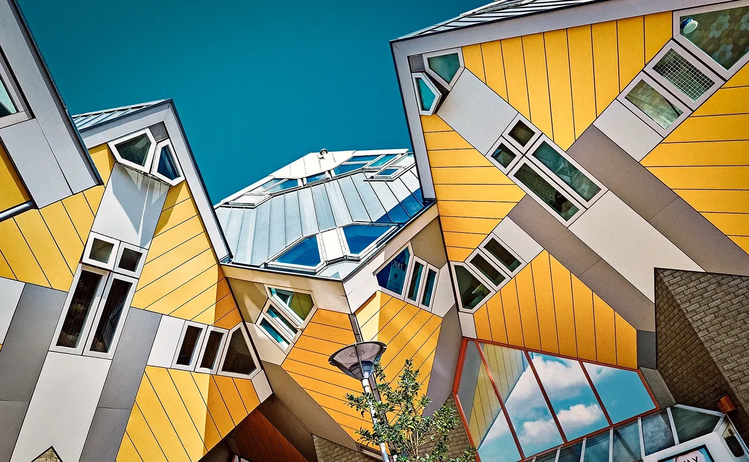 Yellow, cube-shaped houses, tilted at angles, with blue sky background; Rotterdam, Netherlands.