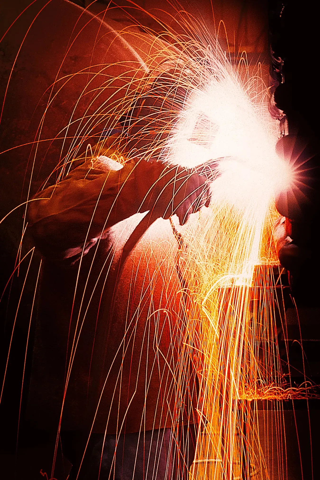 Welder at work, sparks flying, bright orange light.