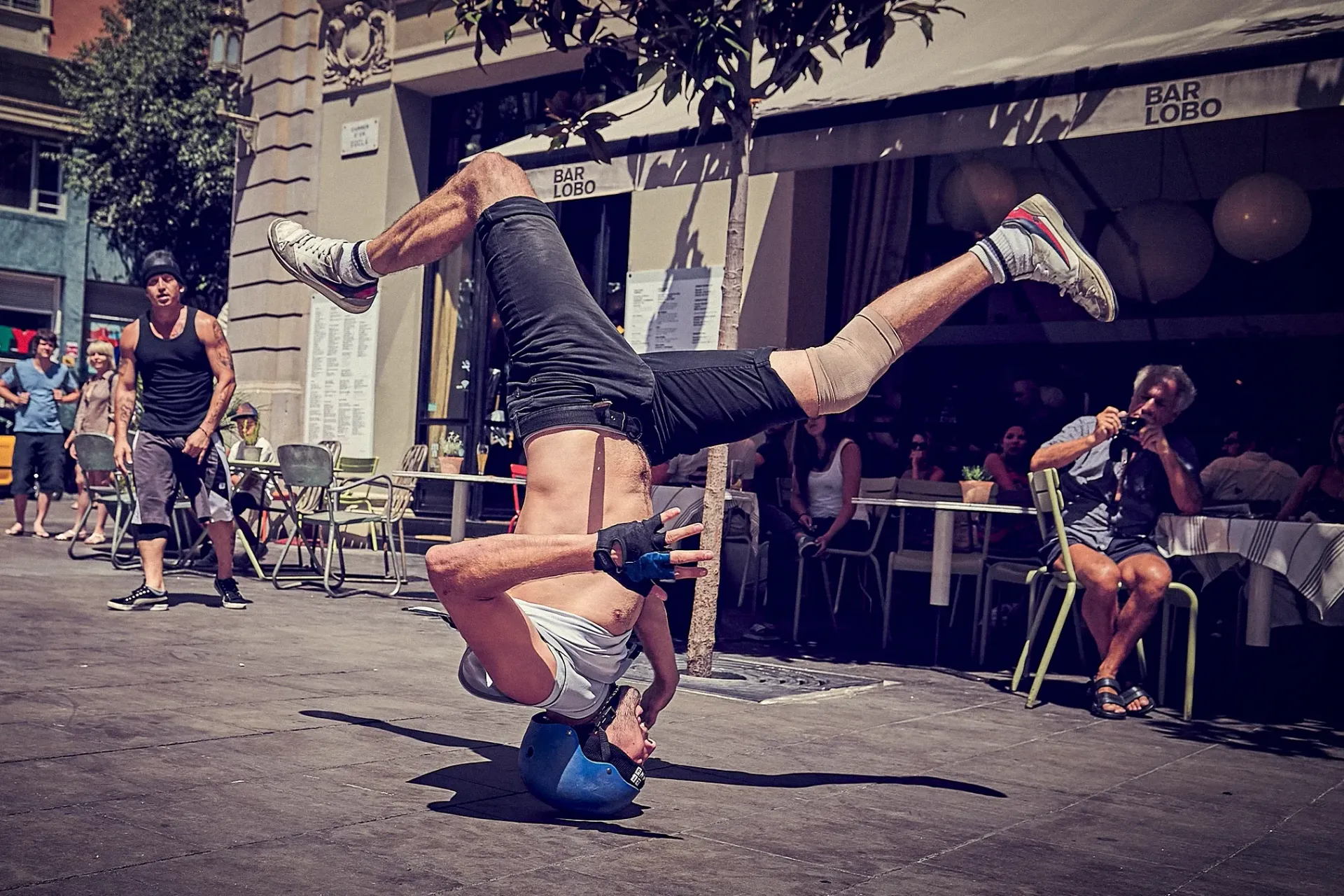 Acrobat balances upside down on his head and a blue ball, street performance.