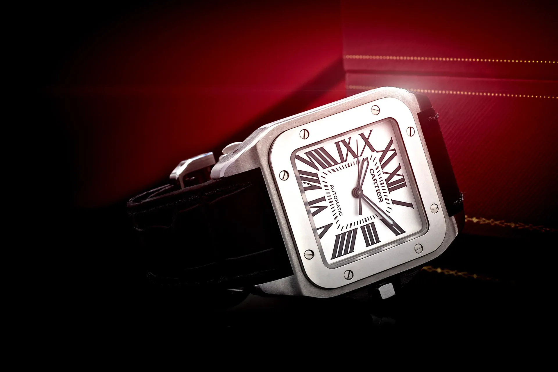 Silver Cartier Santos watch with black strap in a red box.