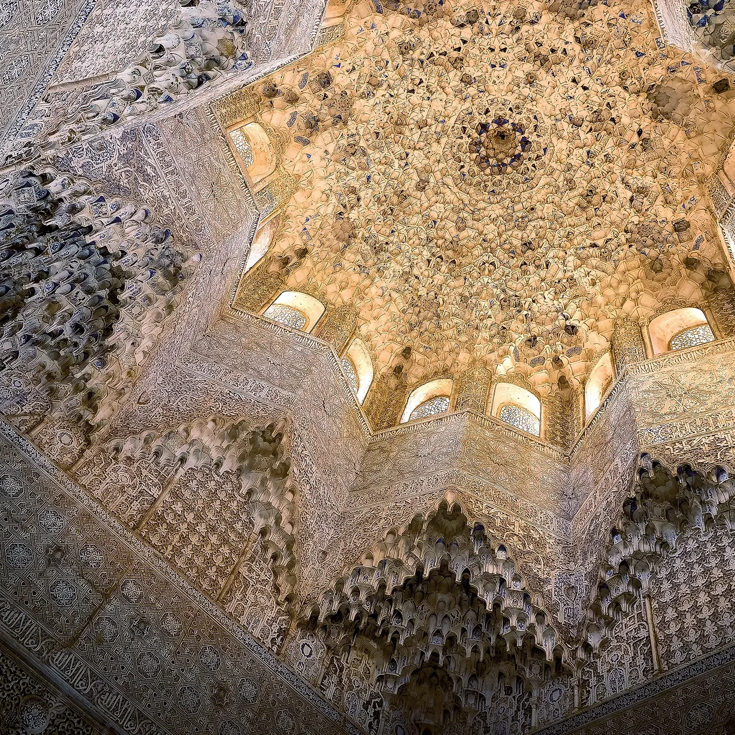 Intricate ceiling with star-shaped dome and arched windows in ornate Moorish architectural style.