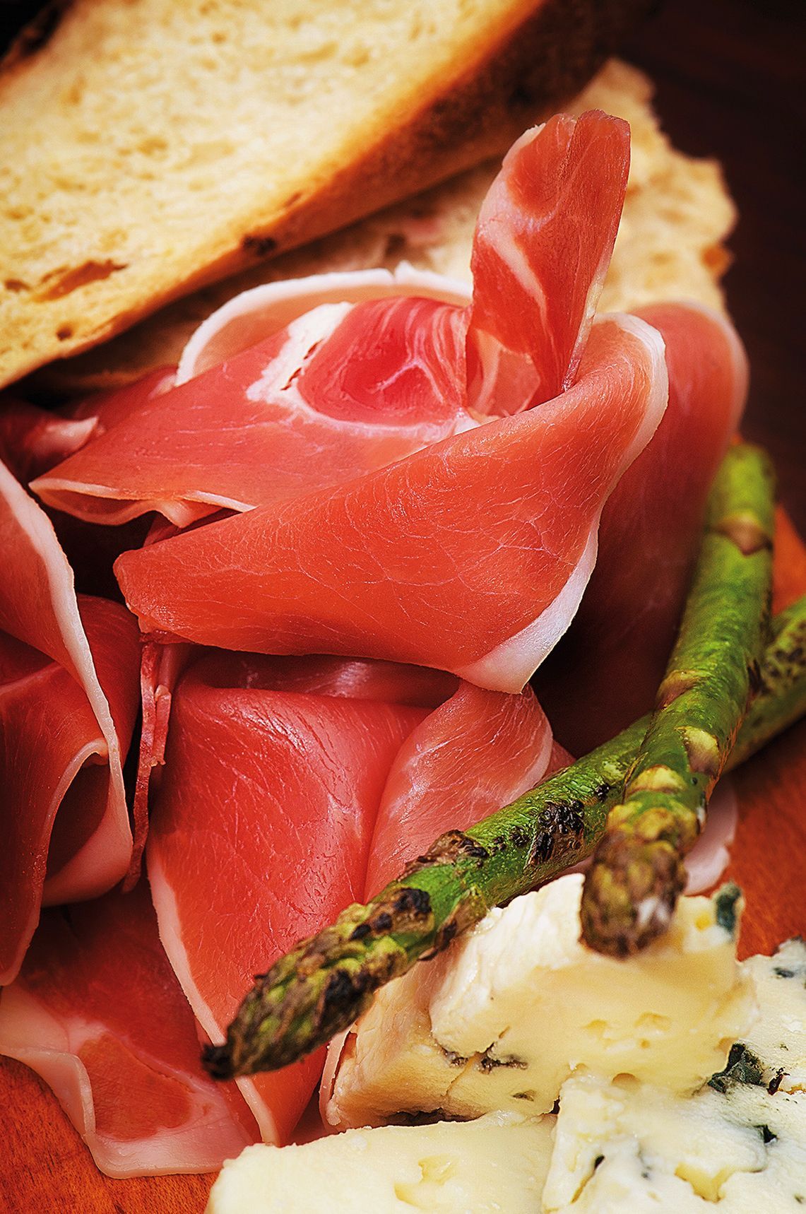 Charcuterie board: prosciutto, asparagus, bread, and assorted cheeses.