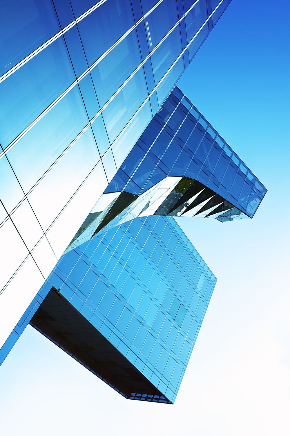 Modern blue glass skyscraper against a bright blue sky.