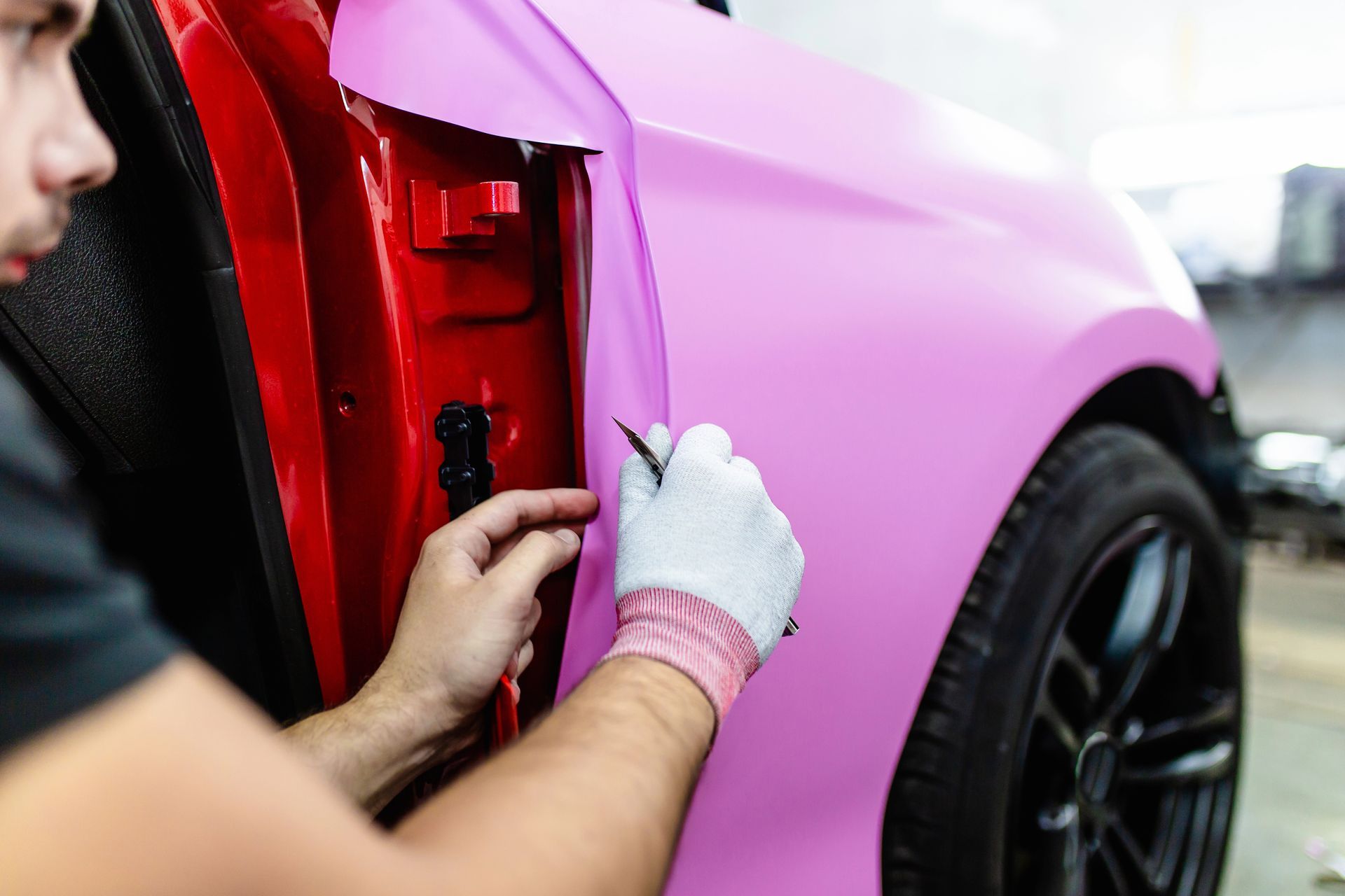 A man is wrapping a pink car with a pink wrap.
