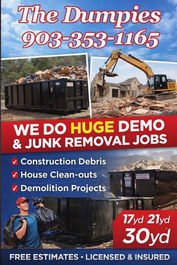 A large black dumpster is sitting on top of a dirt road.
