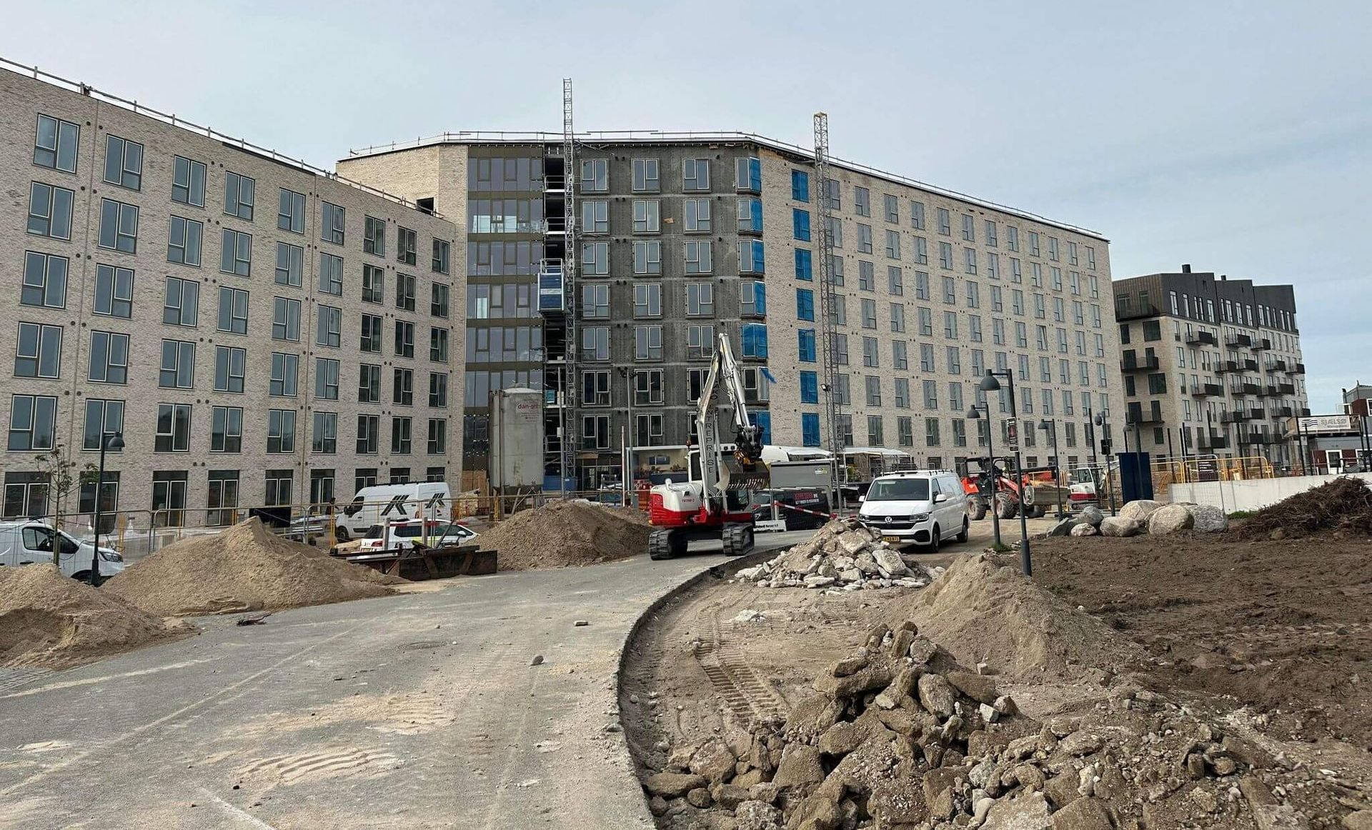 En stor bygning bygges ved siden af ​​en grusvej.
