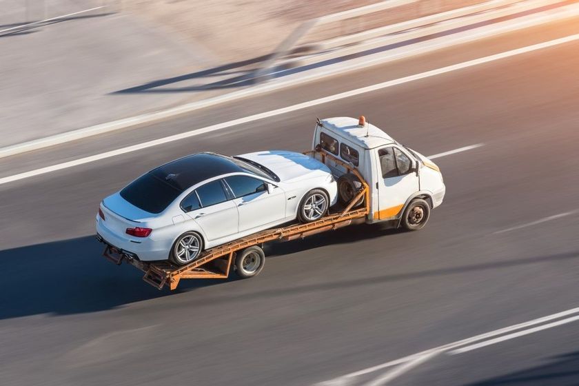 White car being loaded onto a tow truck on a highway.