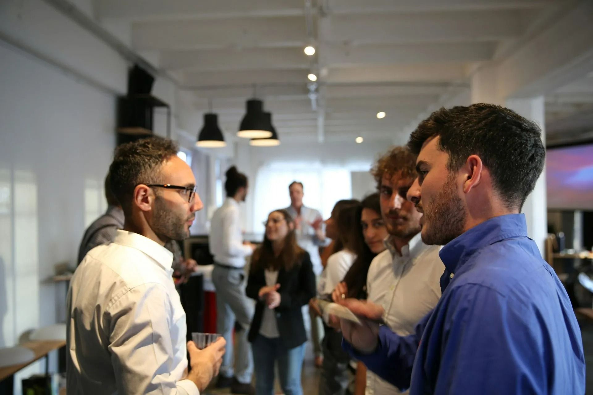 People socializing in an office setting; two men in conversation.