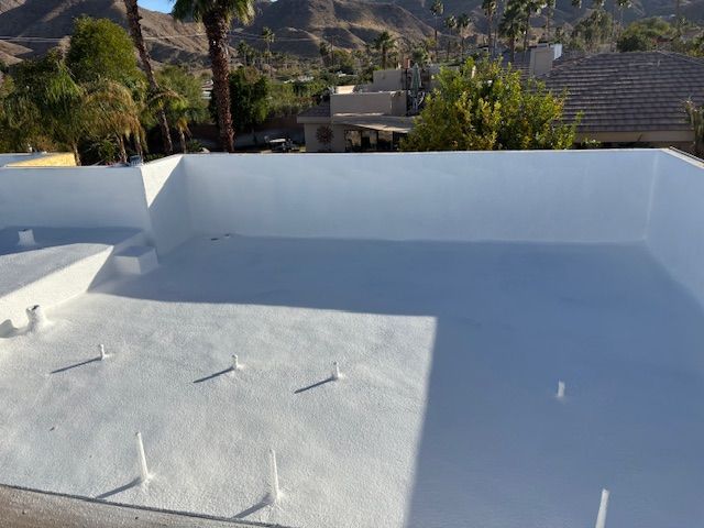 White flat roof with parapet, freshly painted, with a mountain backdrop.