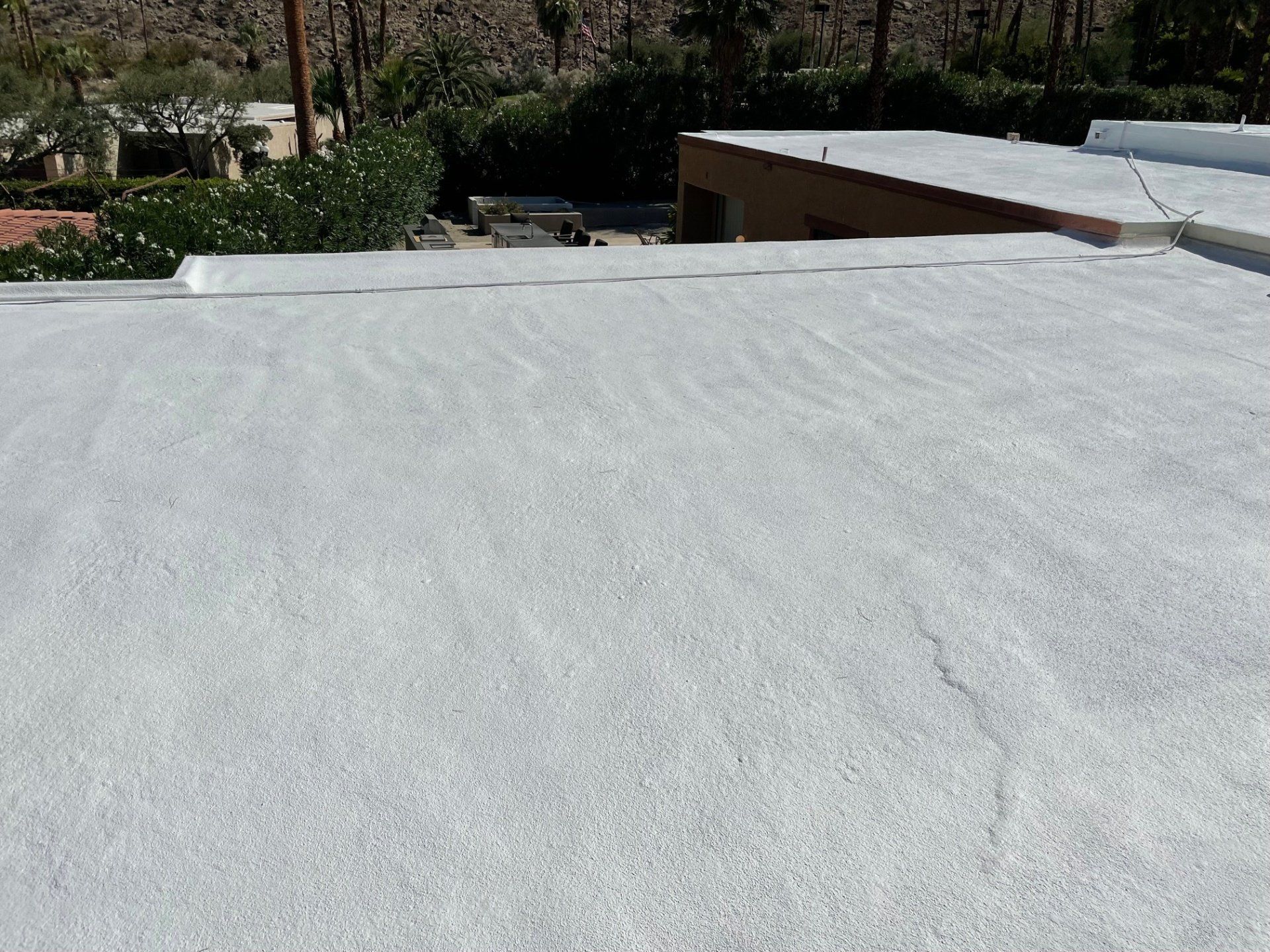 White flat roof with a mountain backdrop and some greenery visible.